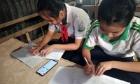 Hai học sinh học trực tuyến chung bằng một chiếc điện thoại