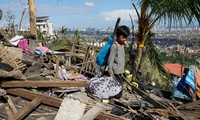 Một bé trai thẫn thờ nhìn căn nhà bị tàn phá do bão Rai ở Cebu (Philippines). Ảnh: AP