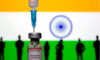 Một đồ chơi hình lọ vắc-xin và mũi tiêm được chụp trước quốc kỳ Ấn Độ. (Ảnh: Reuters)