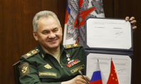 Bộ trưởng Quốc phòng Nga Sergei Shoigu giơ bản lộ trình hợp tác quân sự Nga - Trung đã ký với người đồng cấp Trung Quốc ngày 23/11. (Ảnh: AP)