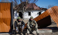Hai lính Ukraine ngồi ở ngôi làng ngoại ô thủ đô Kiev ngày 21/3. (Ảnh: Reuters) 