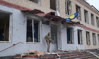 Một lính Ukraine đứng canh trước toà nhà bị hư hại ở làng Barvinkove, tỉnh Kharkiv, ngày 12/4. (Ảnh: Reuters)