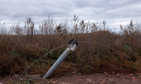 Một tên lửa cắm xuống đất khi một đoạn dây điện đang mắc vào phần đuôi ở Kharkov ngày 21/10. (Ảnh: Reuters)