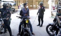 Cảnh sát mang roi bao vây một người đi xe máy trong “khu vực đỏ” về dịch COVID ở quận Meanchey của thủ đô Phnom Penh.
