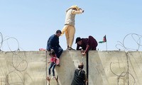 Người dân Afghanistan trèo tường vào sân bay Kabul. Ảnh: Getty
