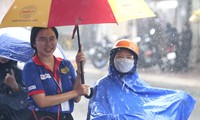 Tình nguyện viên đội mưa che ô cho thí sinh và phụ huynh