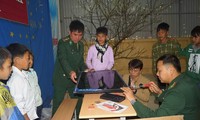 Thượng úy Phạm Tuân (ngoài cùng bên phải) đang lắp đặt chiếc tivi 40 ich mới do anh bỏ tiền túi và kêu gọi bạn bè ủng hộ dành tặng các em học sinh trường THCS Tung Qua Lìn ở huyện Phong Thổ, Lai Châu, tháng 3/2018. Ảnh: Nguyễn Minh 