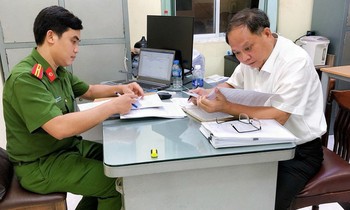 Ông Tất Thành Cang (phải) sau khi nhận quyết định khởi tố bị can, bắt tạm giam, chiều 16/12. Ảnh: Công an cung cấp