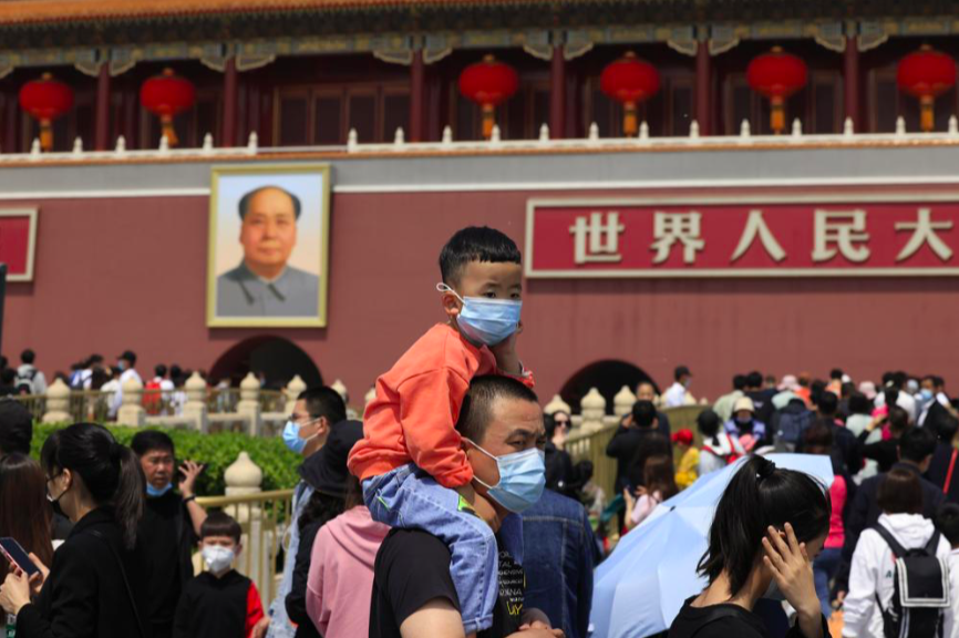 Một bé trai ngồi trên cổ bố khi đi chơi ở quảng trường Thiên An Môn ngày 3/5. Ảnh: AP 