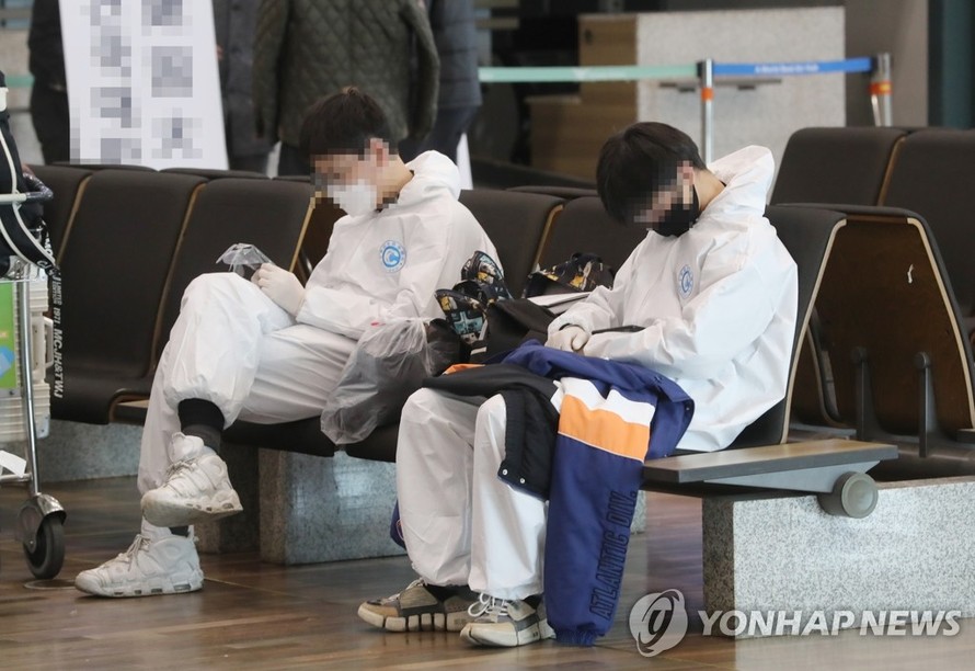 Sinh viên Trung Quốc mặc đồ bảo hộ đang chờ xe đưa đón đặc biệt sau khi đến sân bay Quốc tế Incheon, phía tây Seoul, vào ngày 25/2. Ảnh: Yonhap