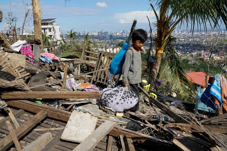 Một bé trai thẫn thờ nhìn căn nhà bị tàn phá do bão Rai ở Cebu (Philippines). Ảnh: AP