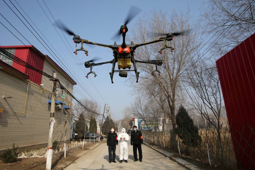 Một tình nguyện viên mặc đồ bảo hộ đang điều khiển drone phun thuốc sát khuẩn trong một ngôi làng ở tỉnh Hà Bắc ngày 31/1. Ảnh: China Daily.