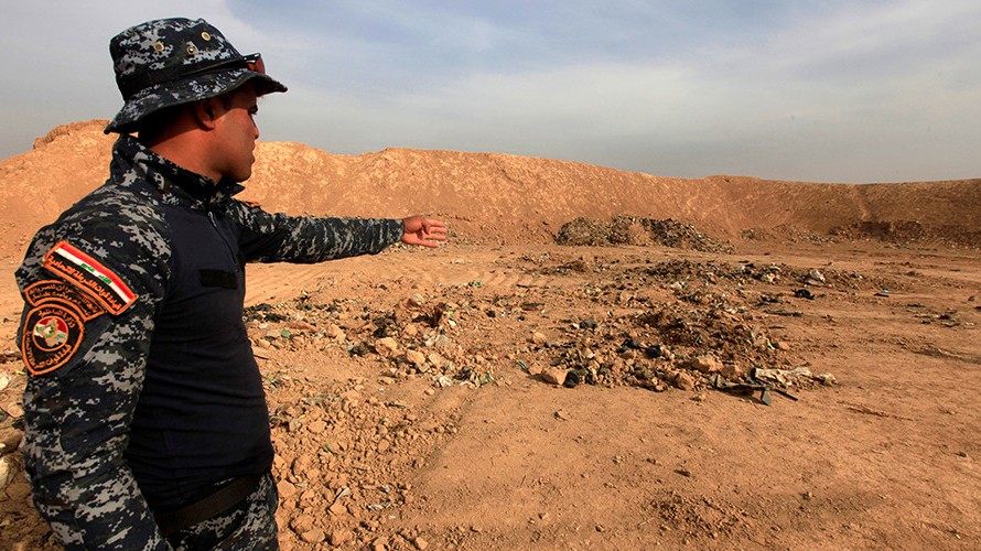 Một binh sỹ Iraq chỉ vào ngôi mộ tập thể ở thị trấn Hammam al-Alil hôm 9/11.