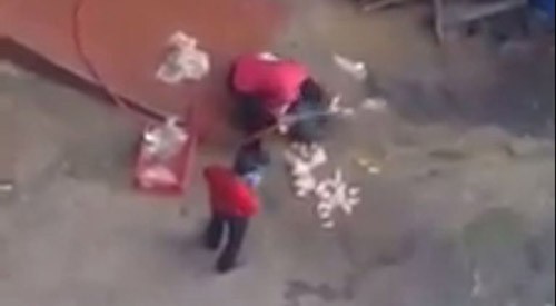 Hai nhân viên bị bắt gặp rửa gà bằng vòi xịt nước trên nền bê tông. Ảnh: Metro.