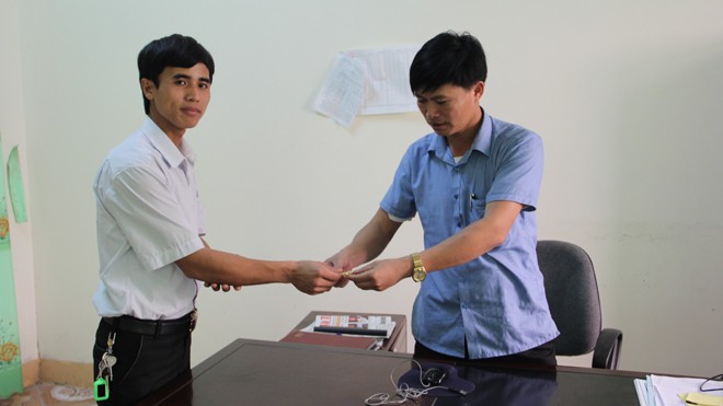 Anh Thành (trái) bàn giao chiếc vòng vàng cho chính quyền xã Cẩm Vịnh