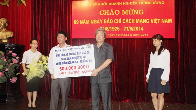 Ông Trần Bá Huấn (áo trắng) trao tặng món quà của VDB. Ông Hà Minh Huệ thay mặt cho các PV tiếp nhận. Ảnh: Trần Việt Hải 