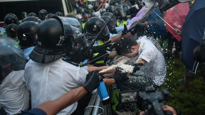 Người biểu tình dùng ô để chống đỡ hơi cay của cảnh sát. Ảnh: Business Insider