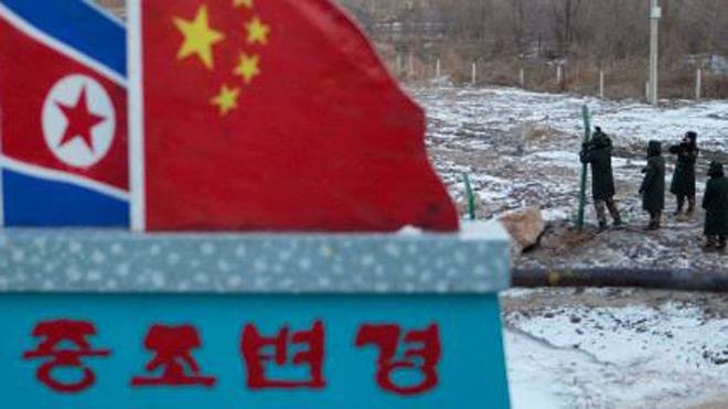 Cảnh sát Trung Quốc xây tường rào gần cột mốc bê tông vẽ cờ Trung Quốc và Triều Tiên với dòng chữ “Biên giới Trung Quốc - Triều Tiên”. Ảnh: AP