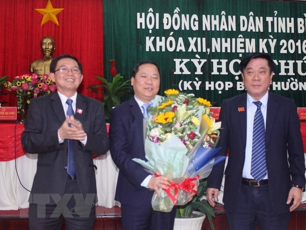 Ông Nguyễn Thanh Tùng, Bí thư Tỉnh ủy, Chủ tịch Hội đồng Nhân dân tỉnh Bình Định (phải) và ông Hồ Quốc Dũng, Chủ tịch Ủy ban Nhân dân tỉnh Bình Định tặng hoa chúc mừng ông Nguyễn Phi Long. (Ảnh: Phạm Kha/TTXVN)