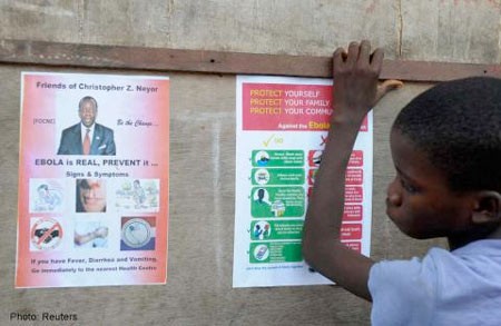 Một cậu bé đứng cạnh tấm áp phích tuyên truyền của chính phủ về bệnh Ebola ở chợ Duwala, Monrovia ngày 17/8/2014.