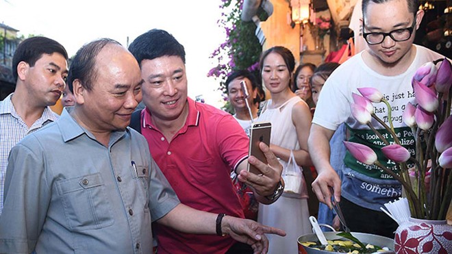 Du khách chụp ảnh kỷ niệm với Thủ tướng Nguyễn Xuân Phúc trên phố cổ Hội An chiều 9/8. Ảnh: Quang Hiếu - VGP.
