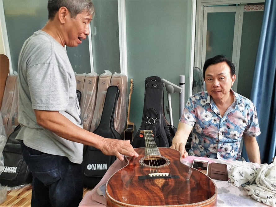 Nghệ sĩ Chí Tài và nghệ nhân làm đàn Ngọc Thức bên cây ghi ta (Ảnh tư liệu của gia đình nghệ nhân)