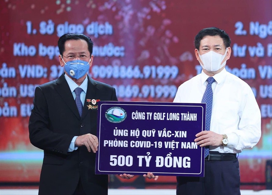 Anh hùng Lao động Lê Văn Kiểm, Chủ tịch Hội đồng quản trị Công ty CP Đầu tư và Kinh doanh Golf Long Thành (trái) trao tặng quỹ vắc-xin phòng, chống COVID-19 số tiền 500 tỷ đồng
