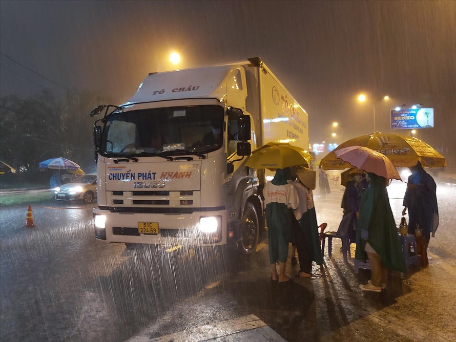 Tình nguyện viên dầm mưa làm nhiệm vụ trong đêm tại một cửa ngõ vào thành phố Cần Thơ. ẢNH: HÒA HỘI