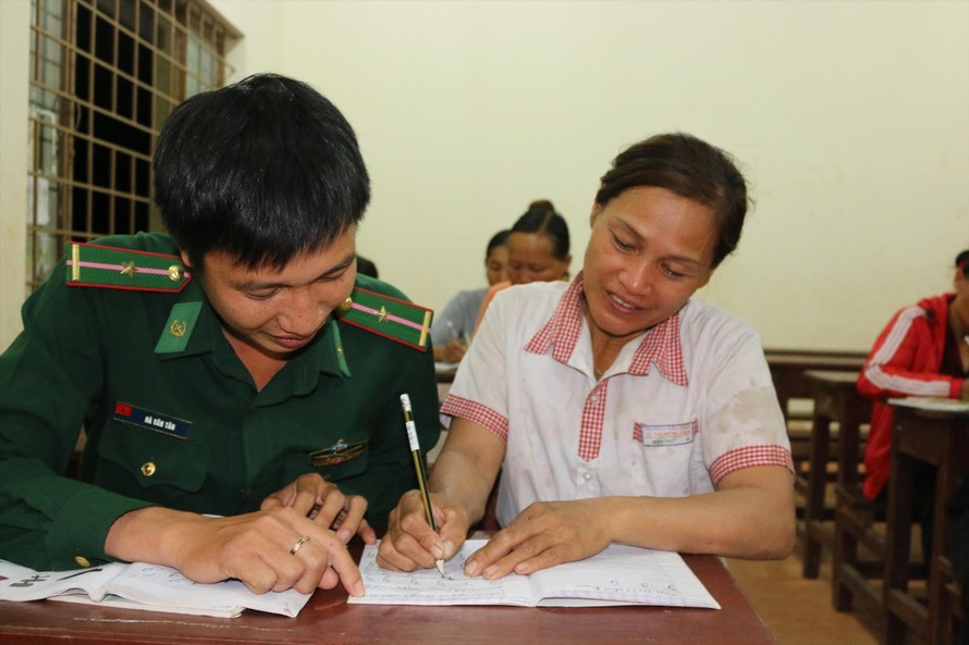 Chiến sĩ Đồn Biên phòng Ea H’leo giúp dân xóa mù chữ. Ảnh: B.N