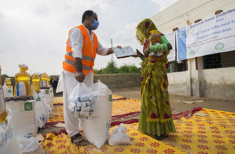 Một nhân viên WFP phát dầu ăn và bột mì cho người dân Pakistan trong tháng 9 vừa qua. Ảnh: WFP 