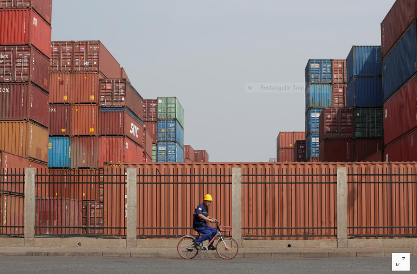 Công nhân đi ngang một trung tâm kho vận ở cảng Thiên Tân, Trung Quốc hôm 16/5. Ảnh: Reuters