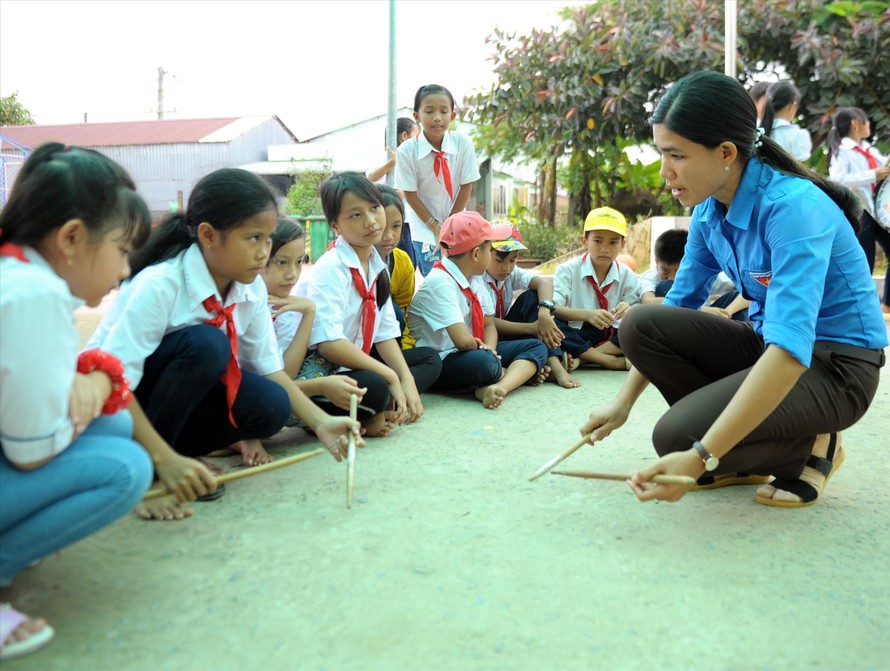 Cô Thạch Thị Bút Pha hướng dẫn học sinh tập gõ, đánh các bài trống Đội trên nền sân trường. Ảnh: Xuân Tùng