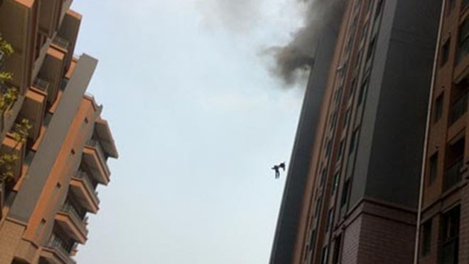 Hai lính cứu hỏa Trung Quốc nắm tay nhau khi ngã khỏi tầng 13 đang nghi ngút khói của một chung cư ở Thượng Hải hôm 1/5. Ảnh: Xinhua