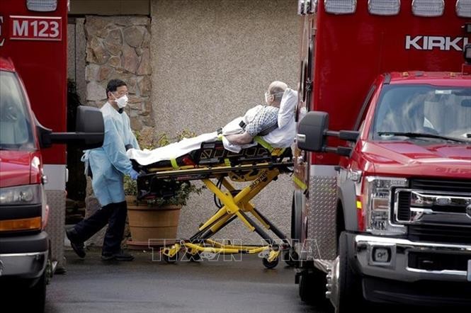 Nhân viên y tế chuyển bệnh nhân nhiễm COVD-19 lên xe cứu thương tại bang Washington, Mỹ. Ảnh: Reuters/TTXVN