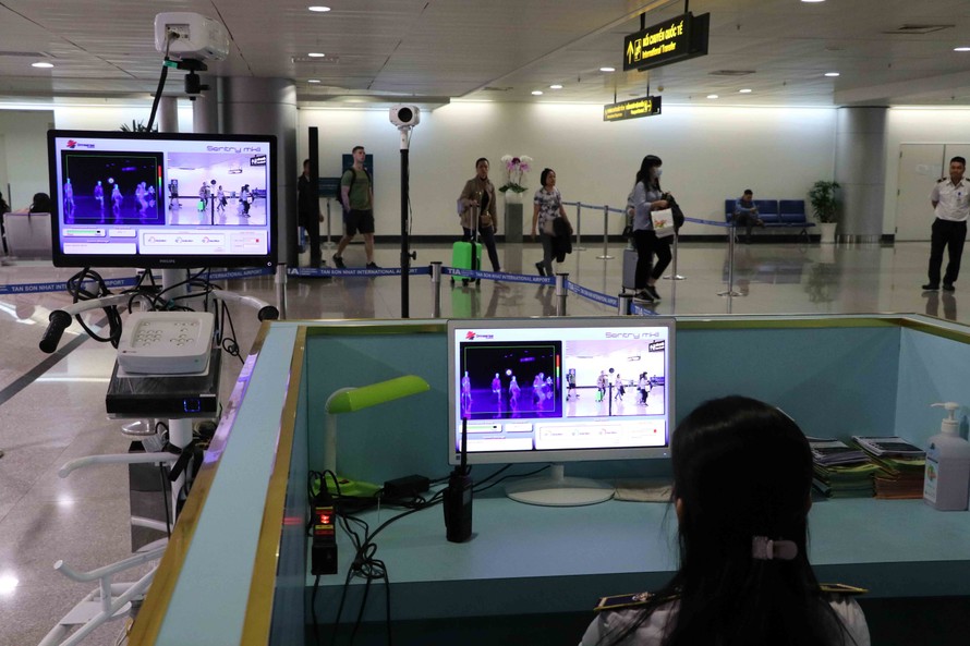 Nhân viên y tế theo dõi thân nhiệt khách quốc tế nhập cảnh vào sân bay Tân Sơn Nhất.