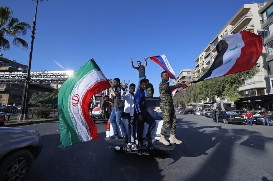Những người ủng hộ chính phủ ông Bashar al-Assad tại Damascus (Syria) vẫy cờ Nga, Iran, Syria nhằm động viên tinh thần binh sĩ nước này sau sự kiện bị Mỹ tấn công. Ảnh: AP