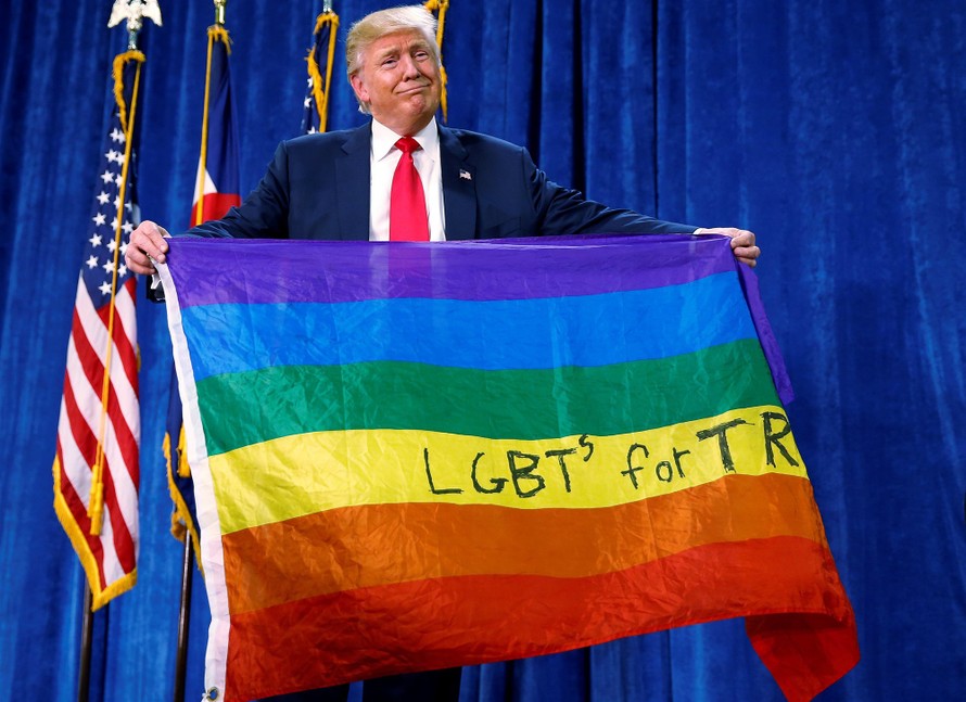 Tổng thống Mỹ Trump cầm lá cờ 7 màu của cộng đồng LGBTQ. Ảnh: Reuters