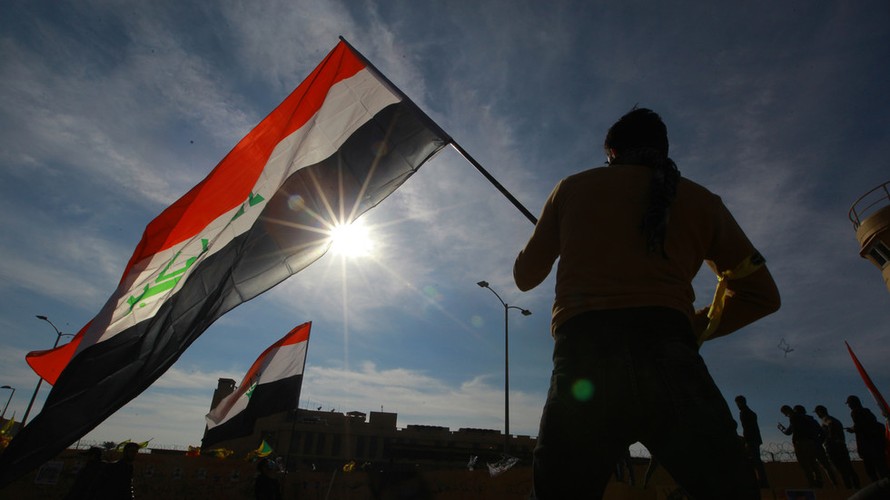 Người biểu tình Iraq cầm quốc kì đứng trước đại sứ quán Mỹ ở Baghdad. Ảnh: Global Look Press