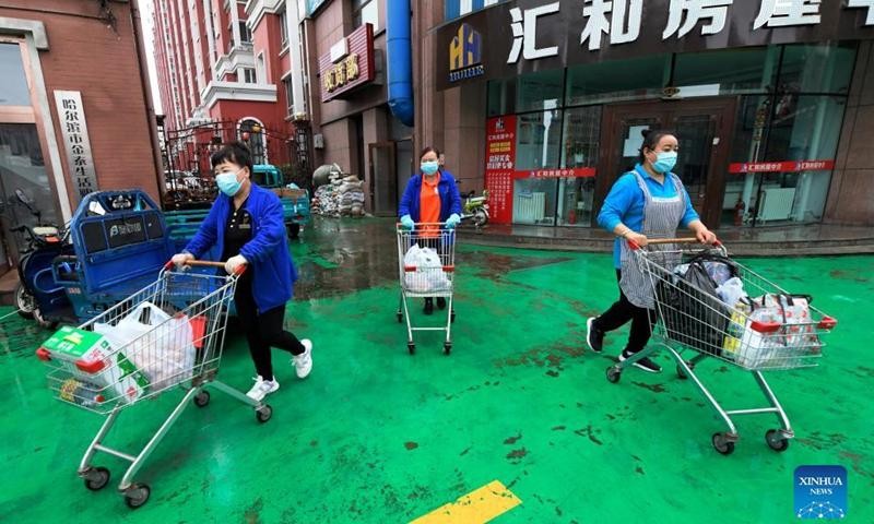 Nhân viên siêu thị vận chuyển nhu yếu phẩm đến nhà người dân ở thành phố Cáp Nhĩ Tân. Ảnh: Xinhua