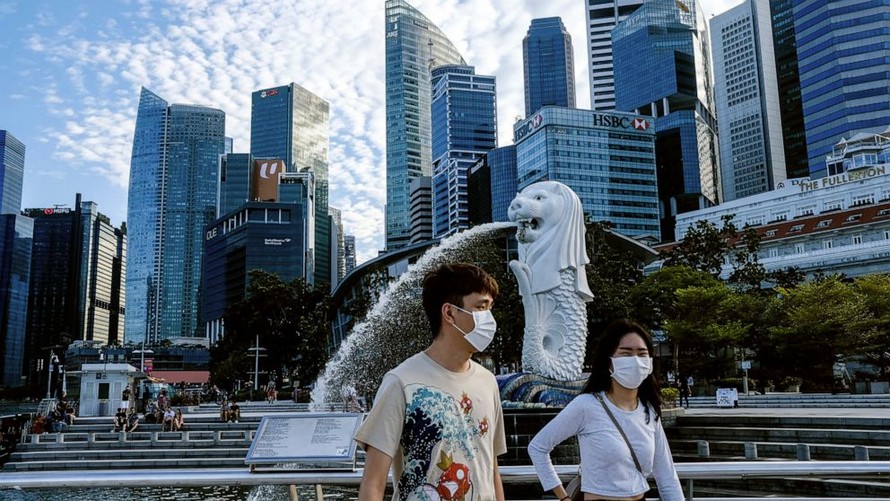 Hai thanh niên đeo khẩu trang đi ngang tượng ngư sư ở Singapore. Ảnh: AP.