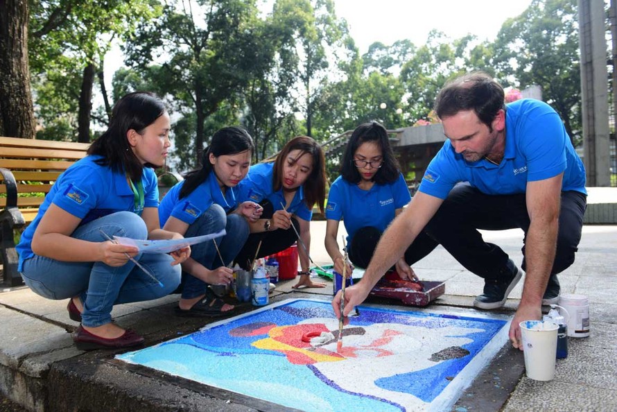 Ông Matt Wilson - Giám đốc Ngoại vụ cấp cao HEINEKEN Việt Nam cùng các tình nguyện viên vẽ trang trí nắp hầm ga trong chương trình “1 Phút Tiết Kiệm Triệu Niềm Vui”