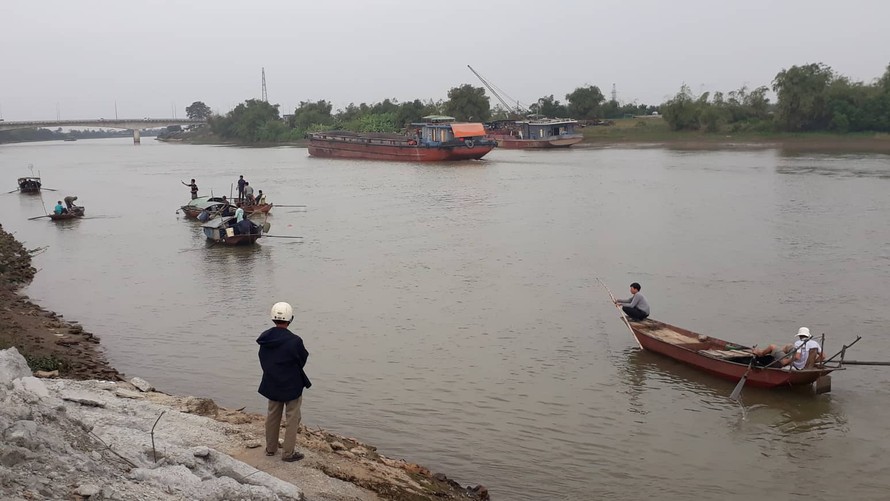 Lực lượng chức năng và người dân vẫn đang tìm kiếm thi thể người vợ bị chìm dưới sông - Ảnh: Hoàng Long