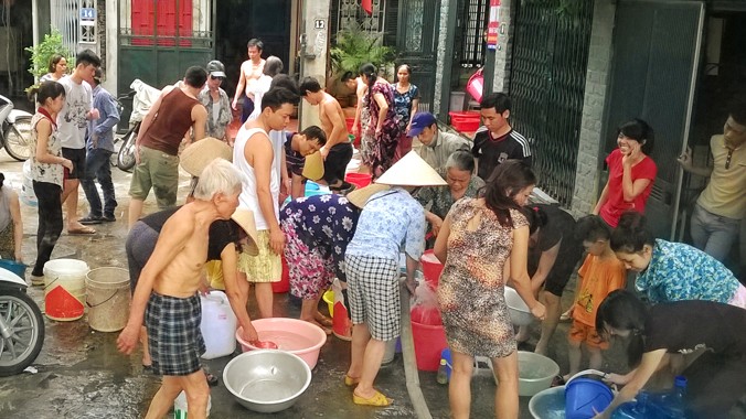 Người dân tại ngõ 362-364 phố Định Công đang mang xô chậu ra để nhận nước sạch từ xe chở nước (Ảnh chụp sáng ngày 23/5). Ảnh: Như Ý - Xuân Phú 