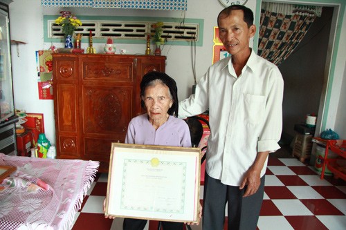 Mẹ Thang cùng bằng tổ quốc ghi công bên người con trai.