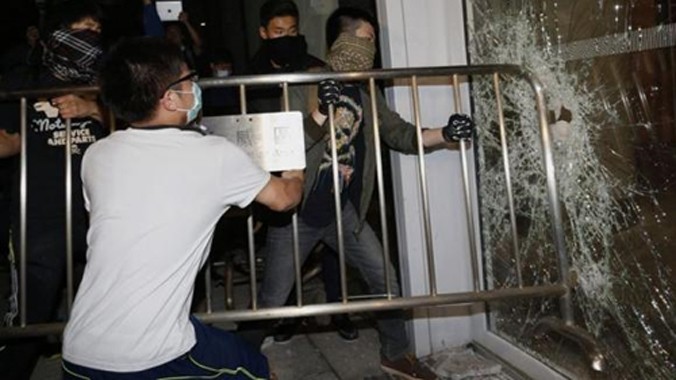 Người biểu tình dùng rào chắn sắt đập cửa kính tại tòa nhà lập pháp. Ảnh: Reuters.