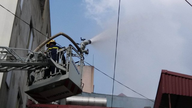 Lính cứu hỏa dùng xe thang chữa cháy.
