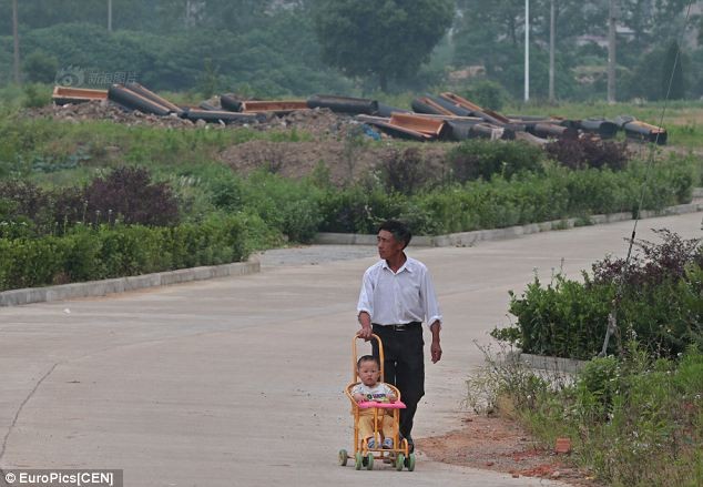 Một ông bố đưa con đi dạo qua đoạn đường có rất nhiều quan tài mới bị đập vỡ ở tỉnh An Huy.