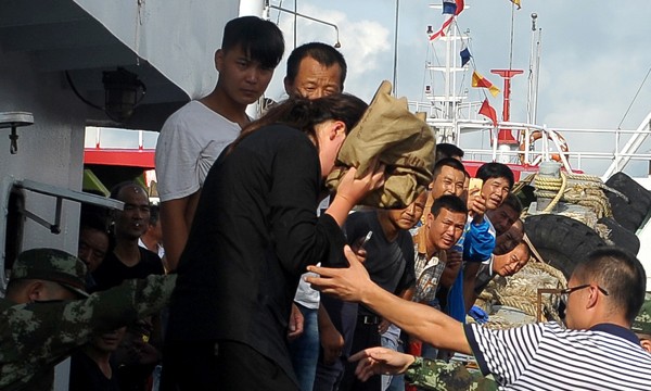 Người phụ nữ Trung Quốc (áo đen, che mặt) được cứu sống sau 38 giờ lênh đênh trên biển.