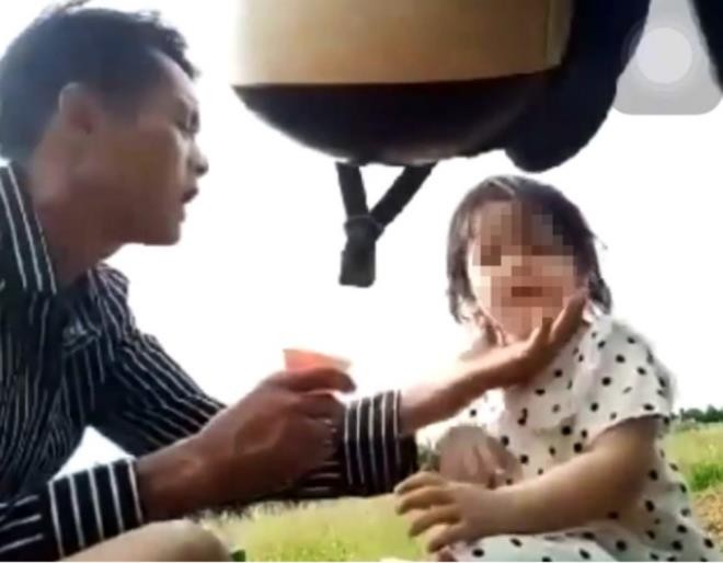 T. ép con gái 3 tuổi uống nước từ chai thuốc màu xanh. (Ảnh: Cắt từ clip)