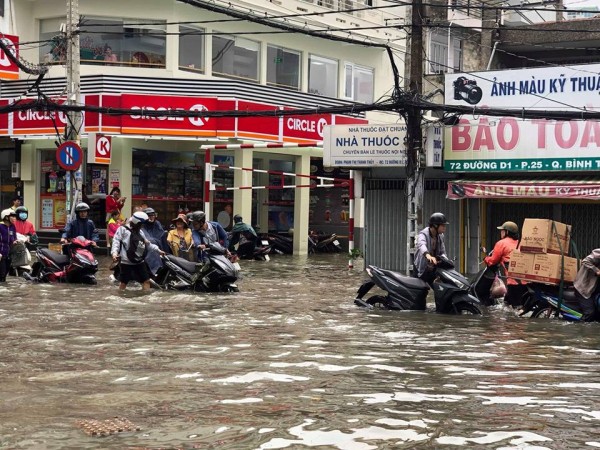 Người dân Sài Gòn di chuyển vất vả trên những con đường ngập đầy nước sau trận bão
